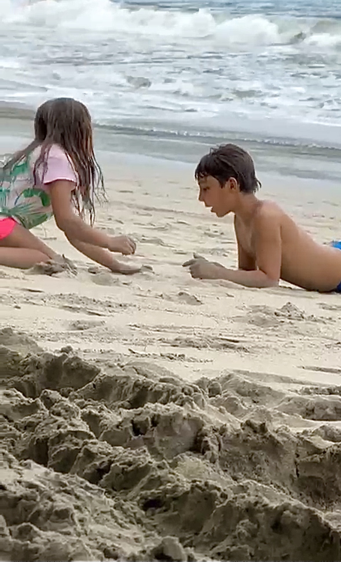 Children building and creating in the sand by the ocean